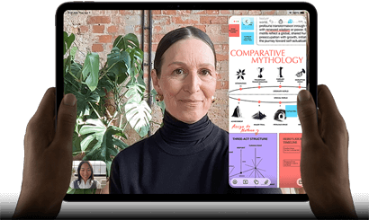 iPad Pro, front exterior, landscape orientation, space black colour, rounded corners, black display bezel, hands holding left and right sides, display showing a FaceTime conversation being live translated, and an educational app showing a presentation of Comparative Mythology with text, diagrams and handwritten notes
