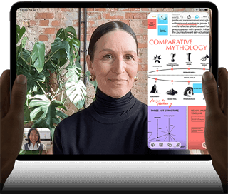 iPad Pro, front exterior, landscape orientation, space black colour, rounded corners, black display bezel, hands holding left and right sides, display showing a FaceTime conversation being live translated, and an educational app showing a presentation of Comparative Mythology with text, diagrams and handwritten notes